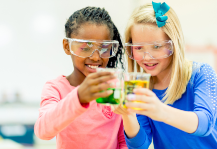 two girls holding coloured beakers