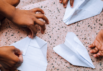 two children folding paper airplanes