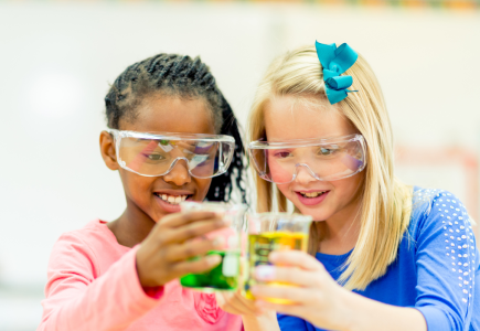 two girls holding coloured beakers