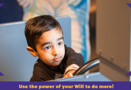 A boy in black t-shirt holding on to a steering-wheel replica