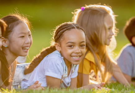 five children laying on grass at sunset smiling