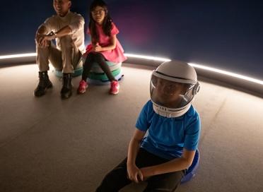 Child in astronaut helmet sits in a star show